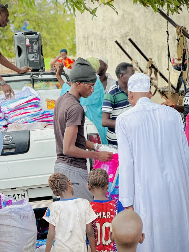 Omar handing a packed mosquito net from the back of a pickup to people waiting in a village
