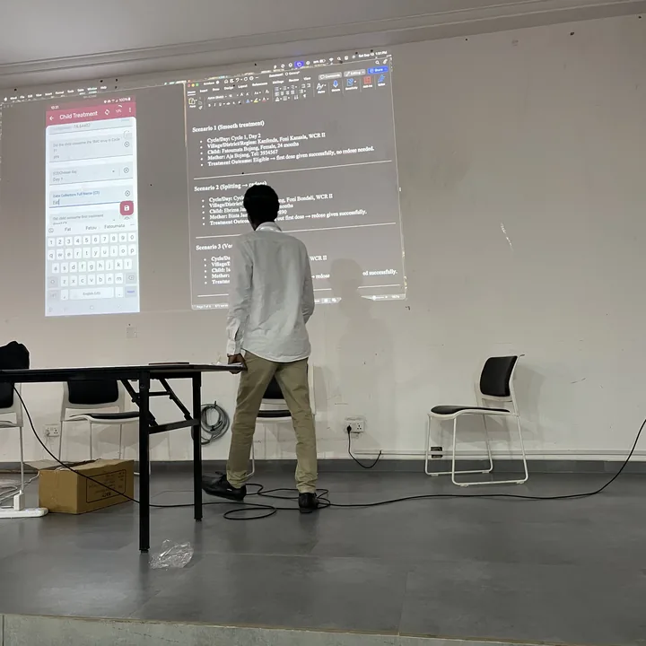 Omar presenting at the front of a training room, with the SMC child-treatment form projected on the wall